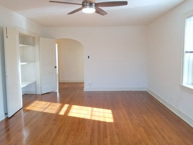 an empty living room with wood floors and a ceiling fan