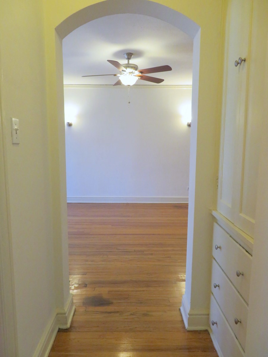 an empty room with a ceiling fan and white walls