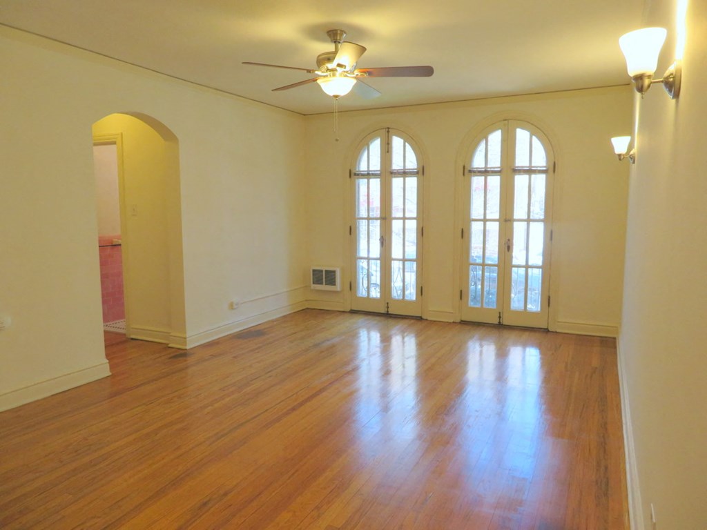an empty living room with wood floors and a ceiling fan