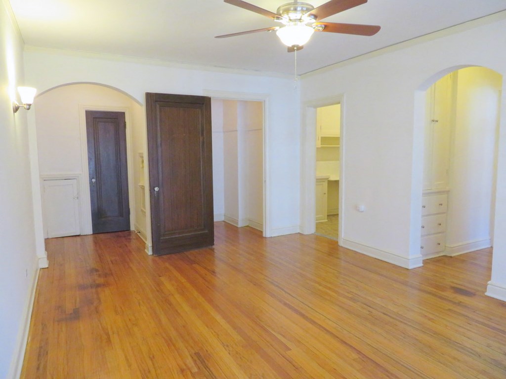 an empty living room with wooden floors and a ceiling fan