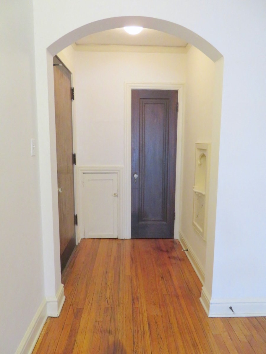 a hallway with a wooden floor and a door to a closet