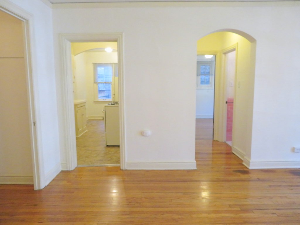 an empty living room with a hard wood floor and white walls