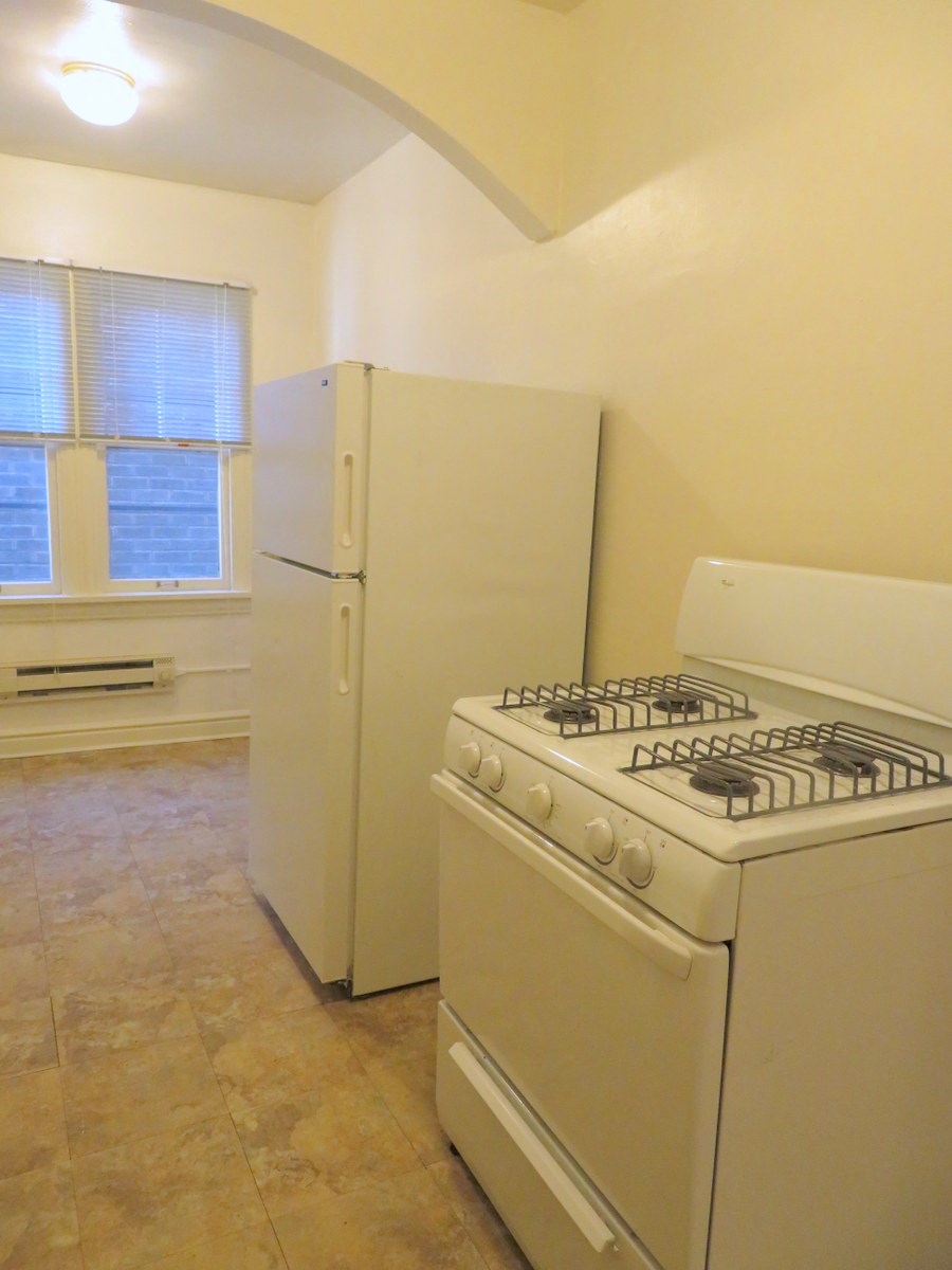 an empty kitchen with a stove and a refrigerator