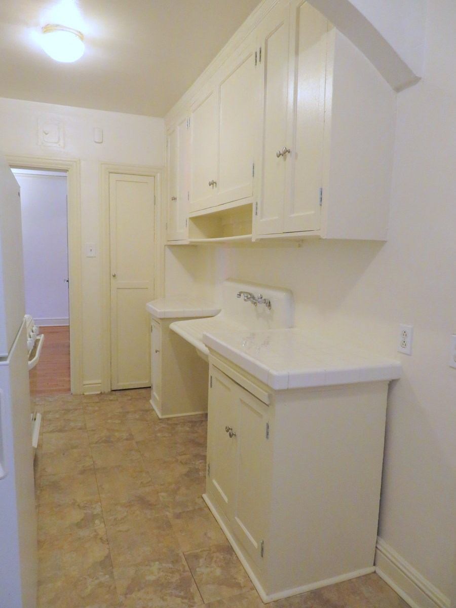 an empty kitchen with white cabinets and a sink