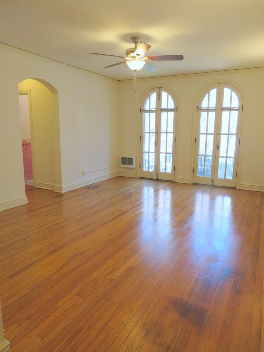 an empty living room with wood floors and a ceiling fan