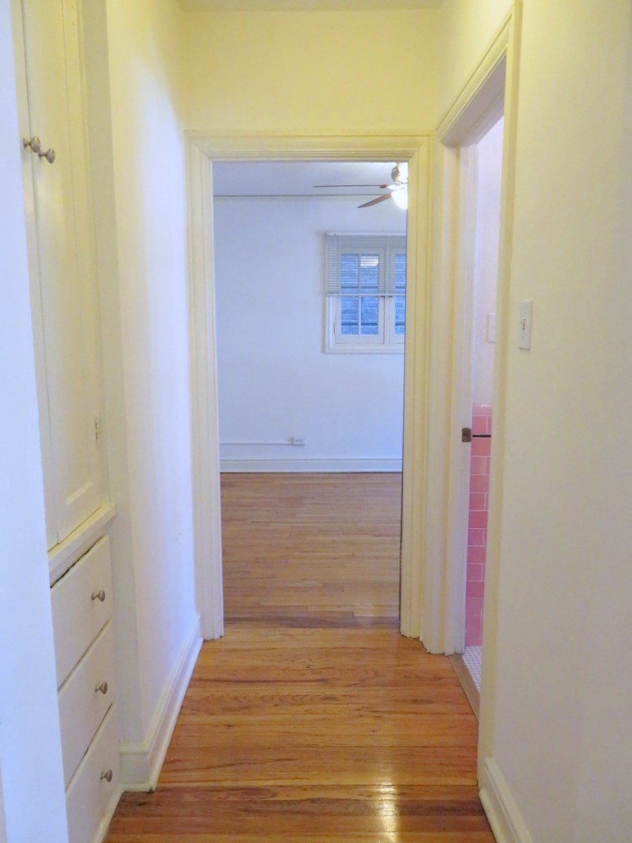 a hallway with a wood floor and white walls and a window