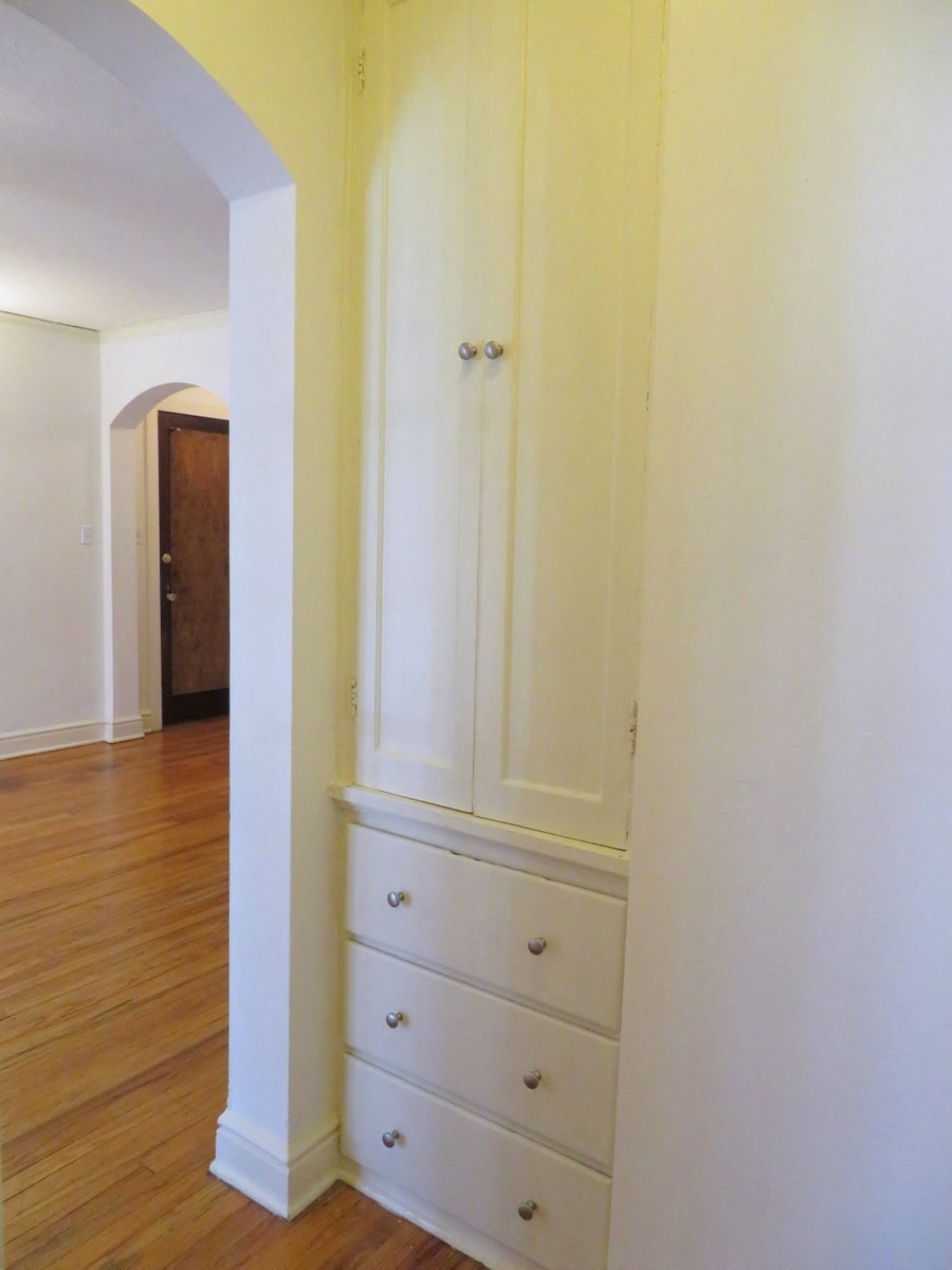 a view of the dresser in the hallway of a house with a wood floor