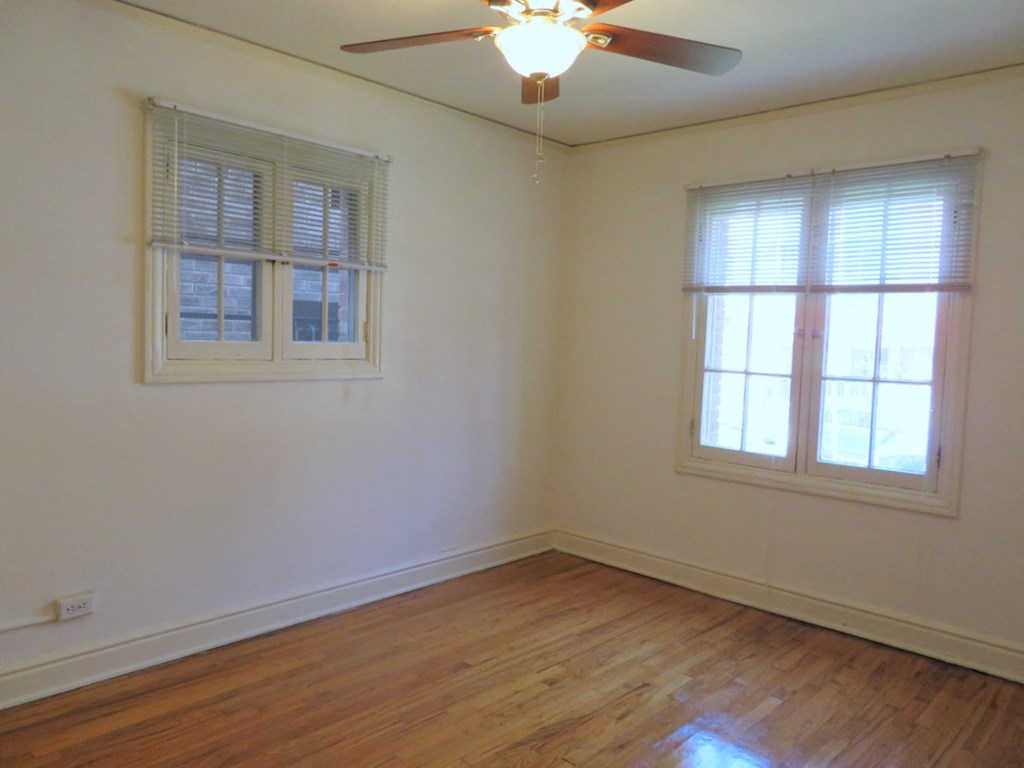 an empty room with a ceiling fan and two windows