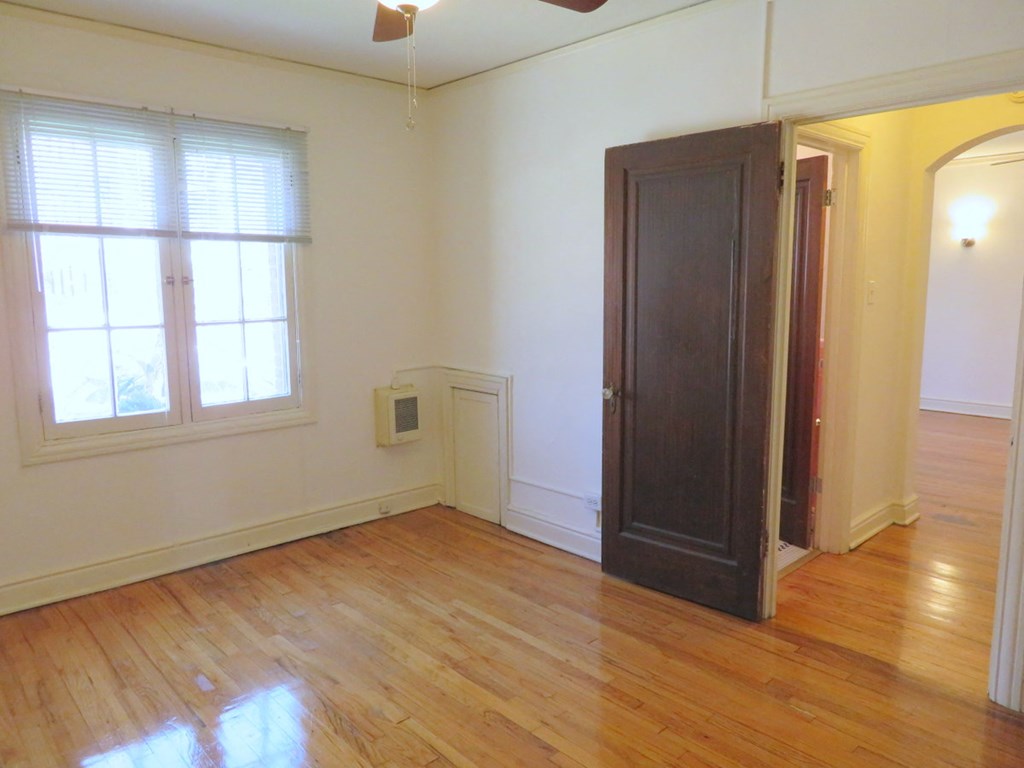 an empty living room with a wooden floor and a black door