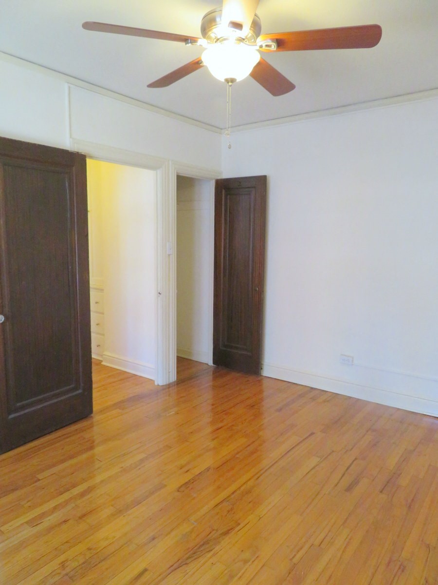 an empty living room with wood floors and a ceiling fan