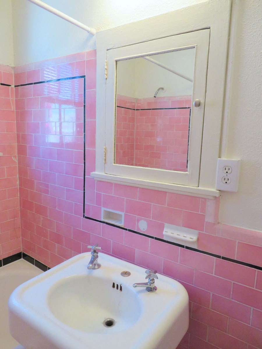 a pink bathroom with a sink and a mirror