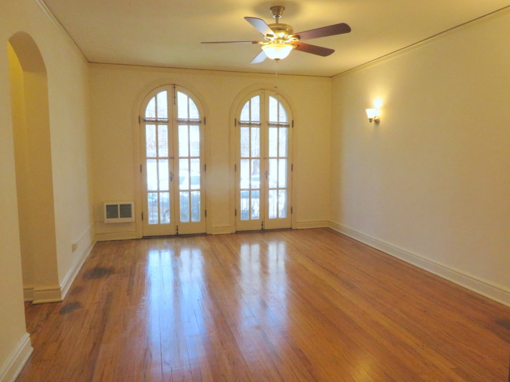 an empty living room with wood floors and a ceiling fan