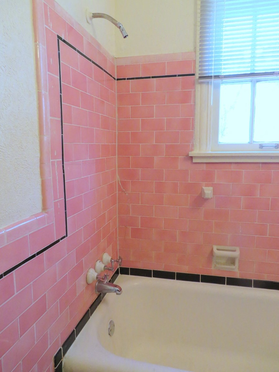 a pink tiled bathroom with a tub and a window
