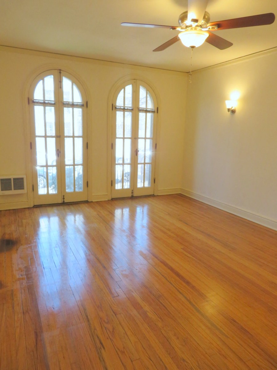 an empty living room with wood floors and a ceiling fan
