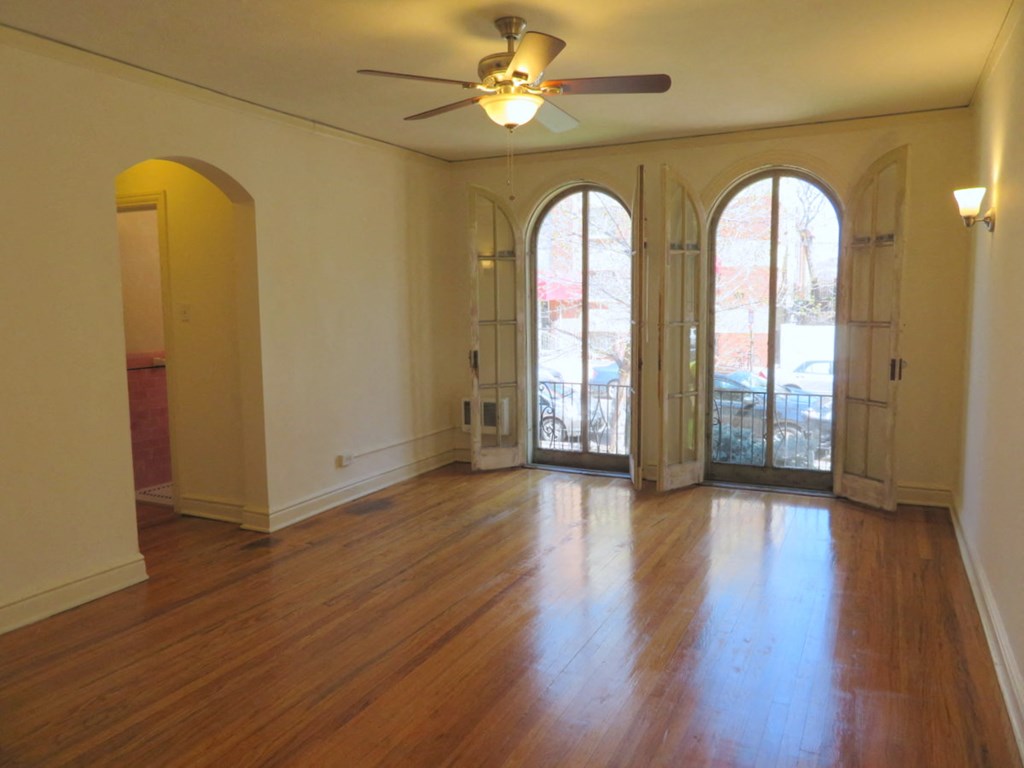 an empty living room with wood floors and a ceiling fan