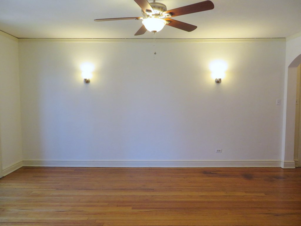 an empty living room with a ceiling fan and a wood floor