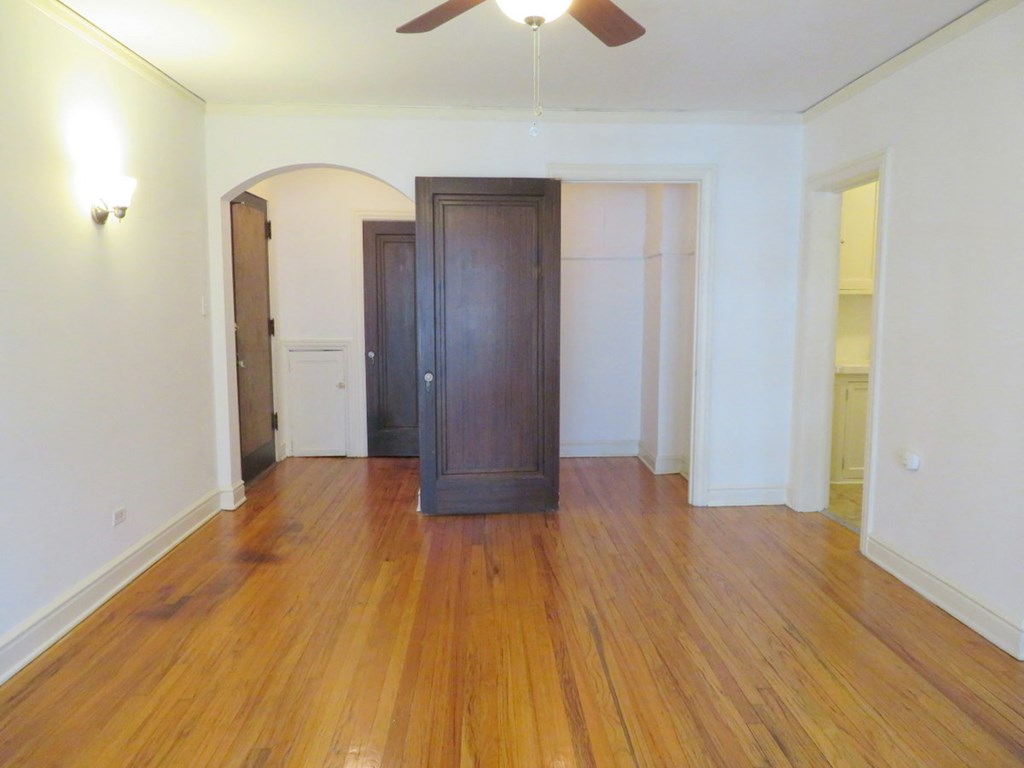 an empty living room with wood floors and a wooden door