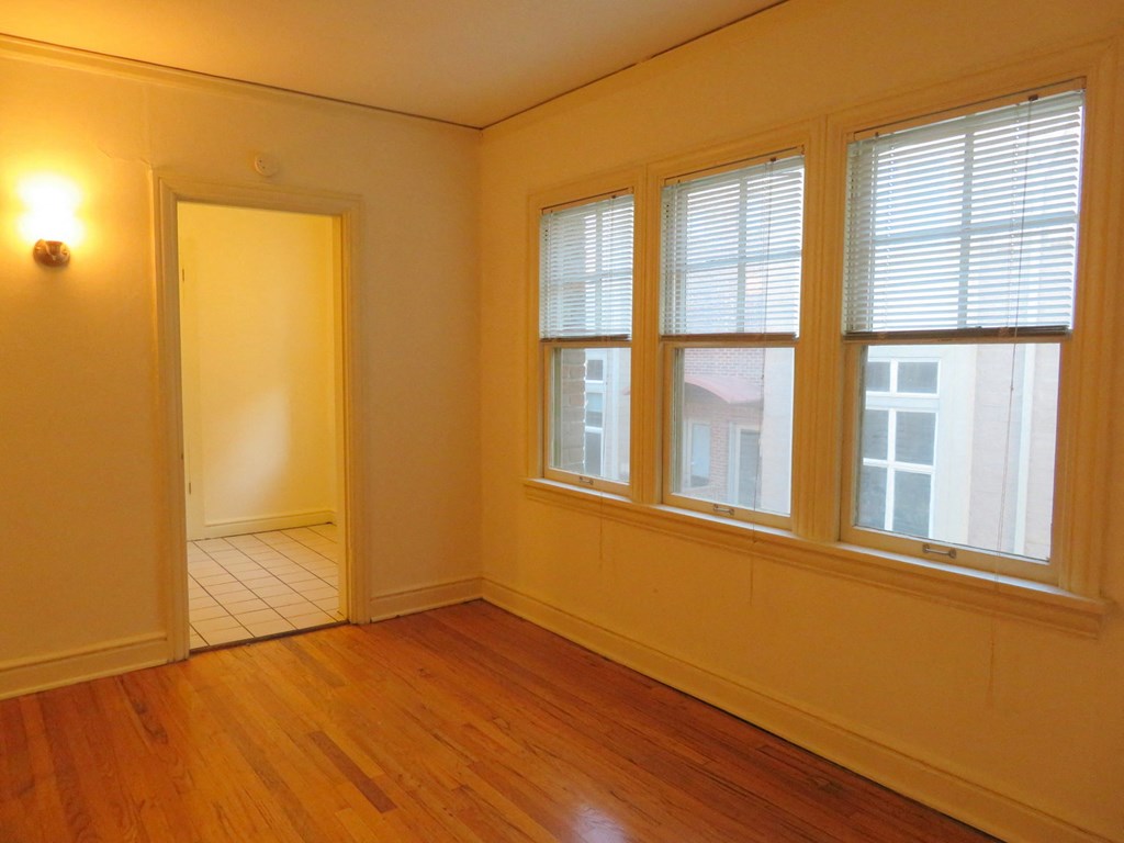 the living room of an empty house with a wooden floor and windows