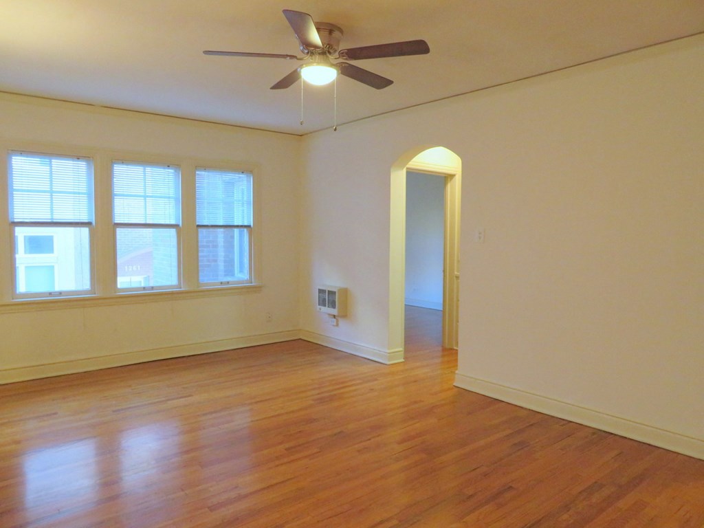 an empty living room with a ceiling fan and wood floors