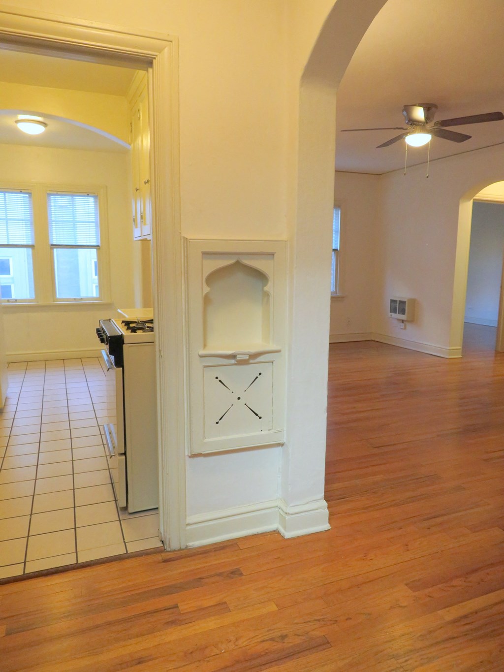 an empty living room with an open door to a kitchen