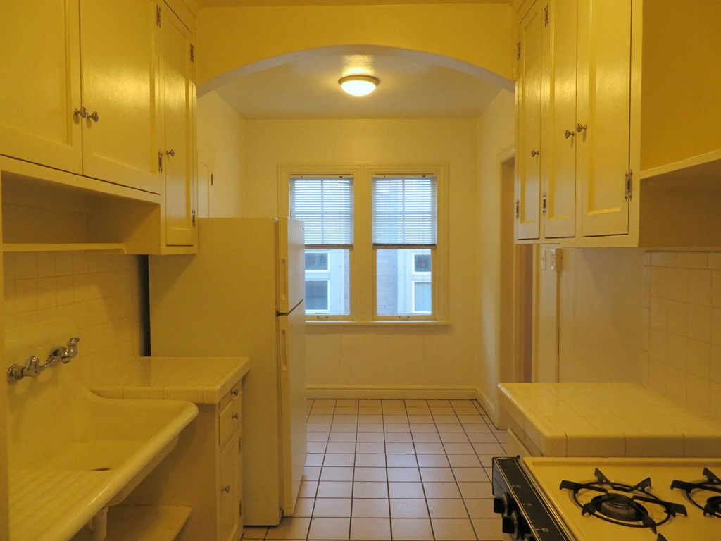 a kitchen with white cabinets and a stove and a window