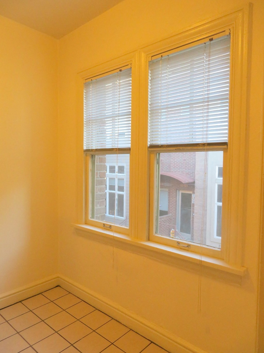 the corner of a room with two windows and a tiled floor
