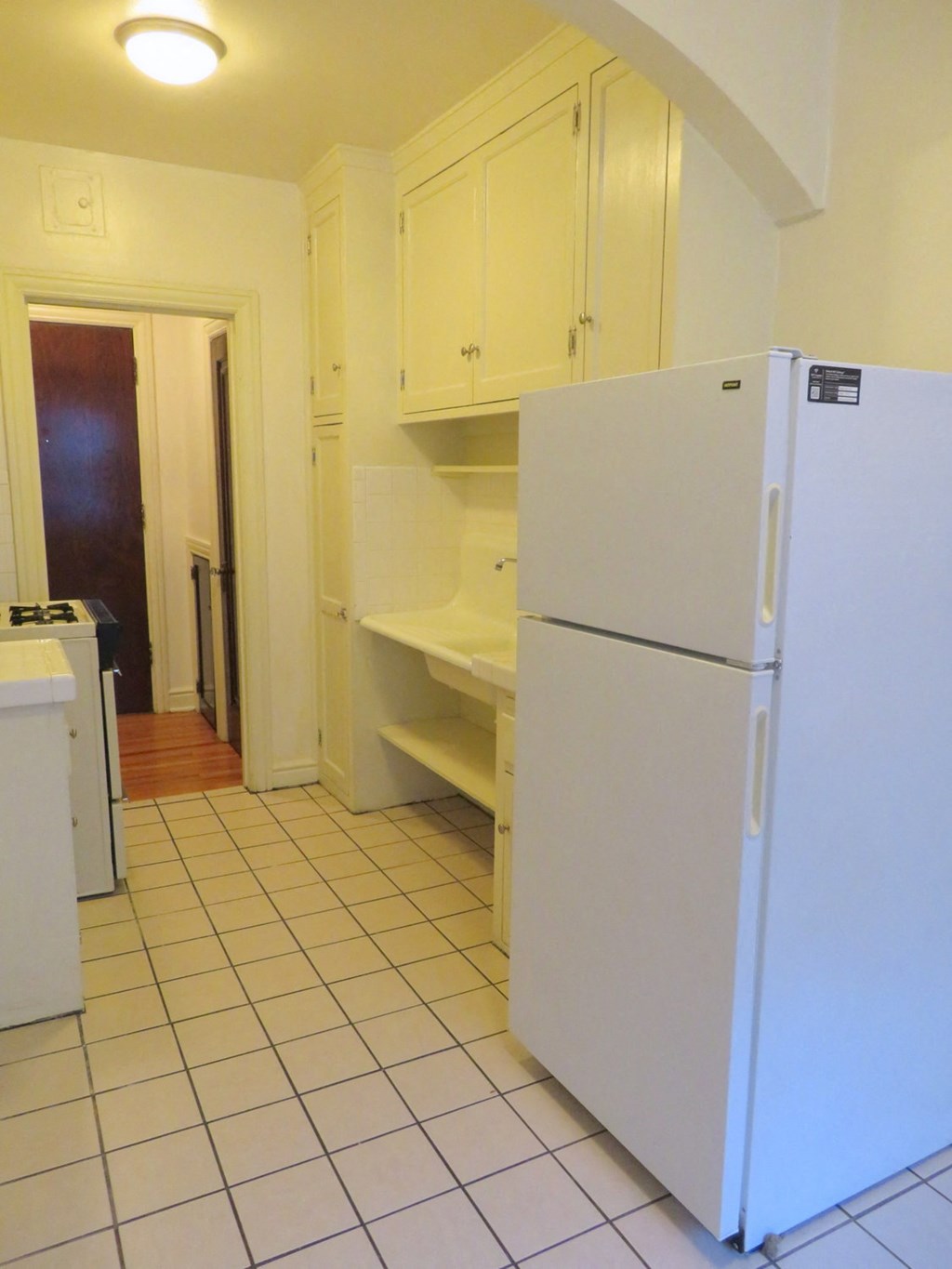 an empty kitchen with a refrigerator and cabinets