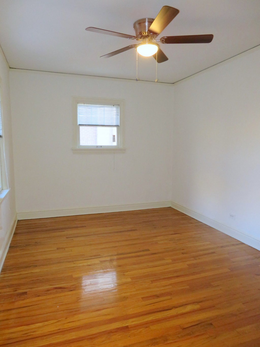 an empty room with wooden floors and a ceiling fan