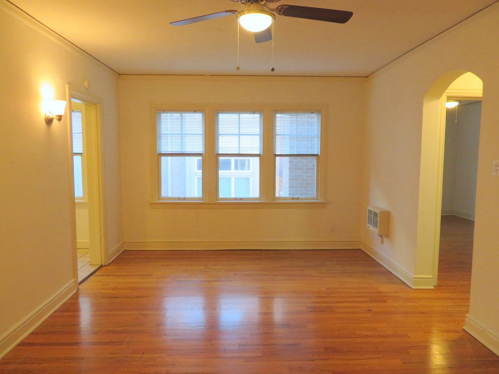 an empty living room with a ceiling fan and a window