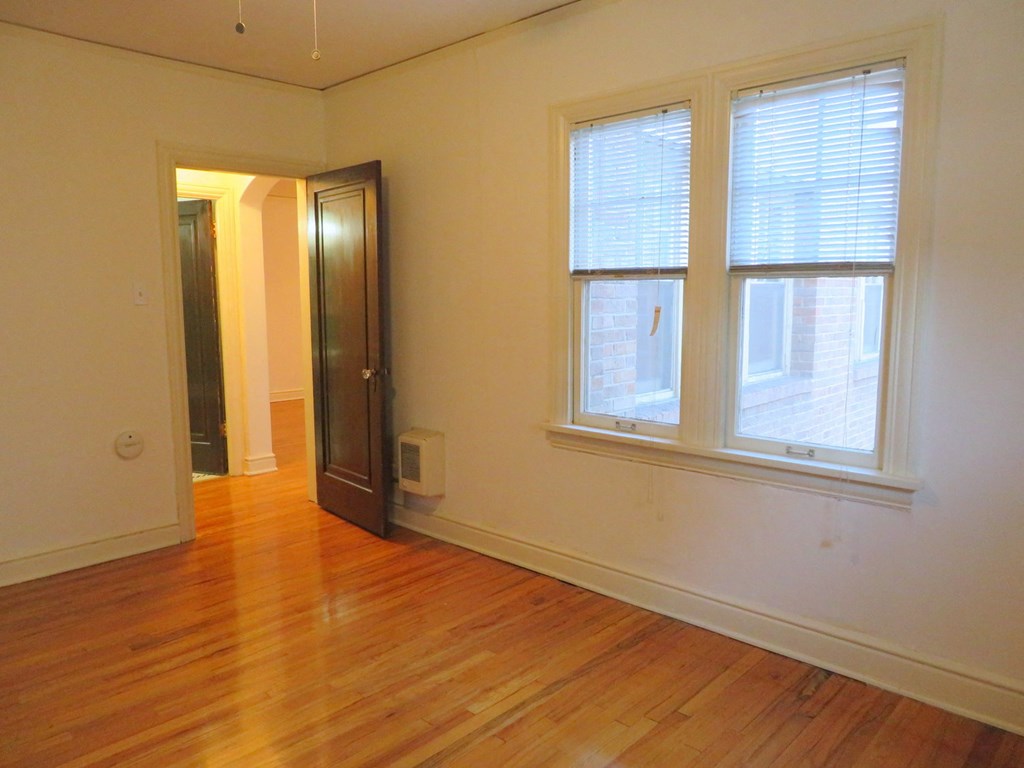 an empty living room with wood floors and a window