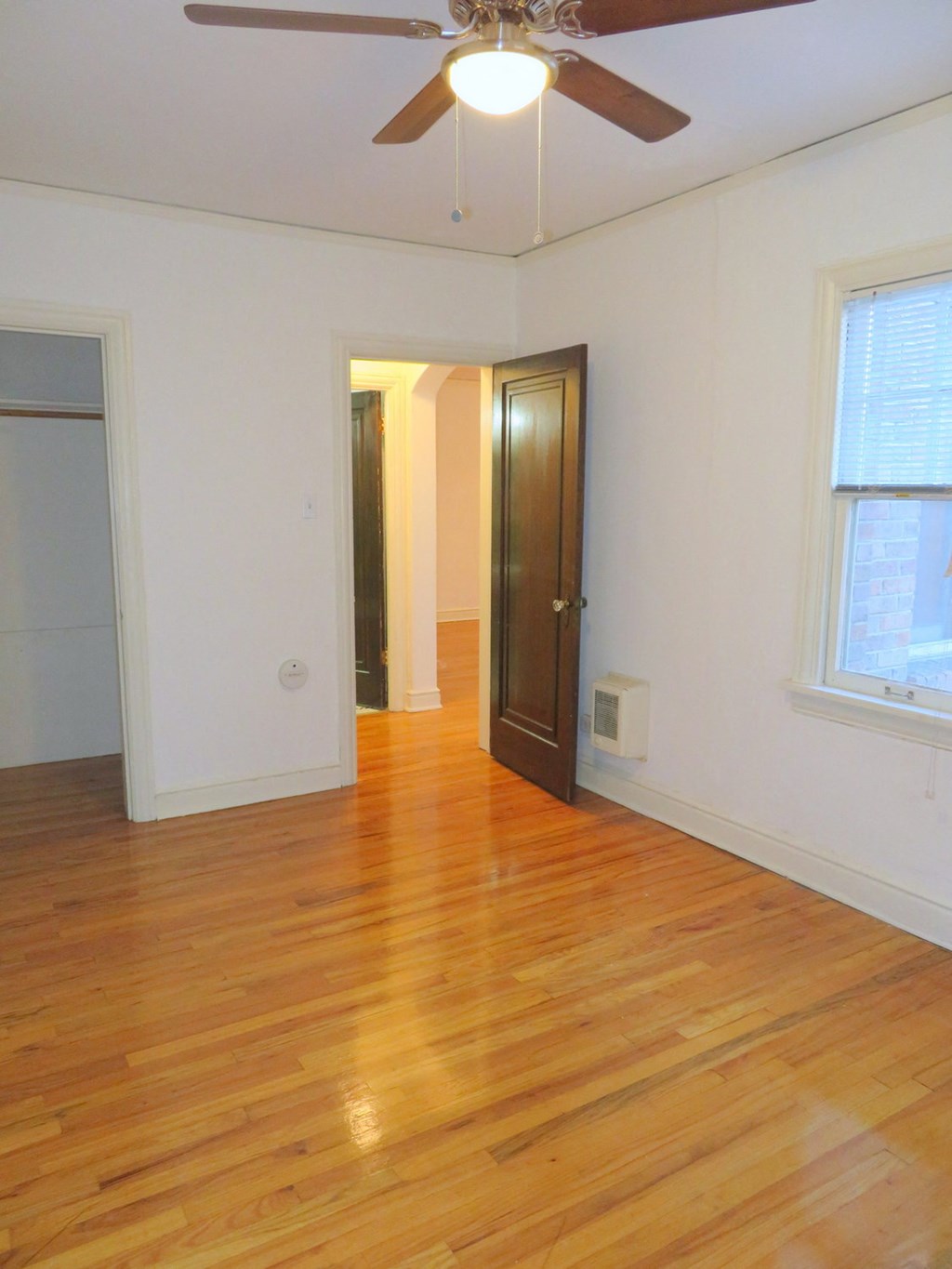an empty living room with wood floors and a ceiling fan