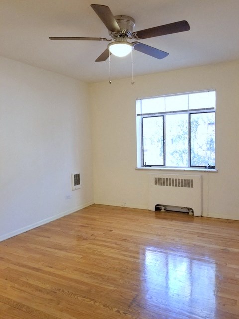an empty living room with a ceiling fan and a window