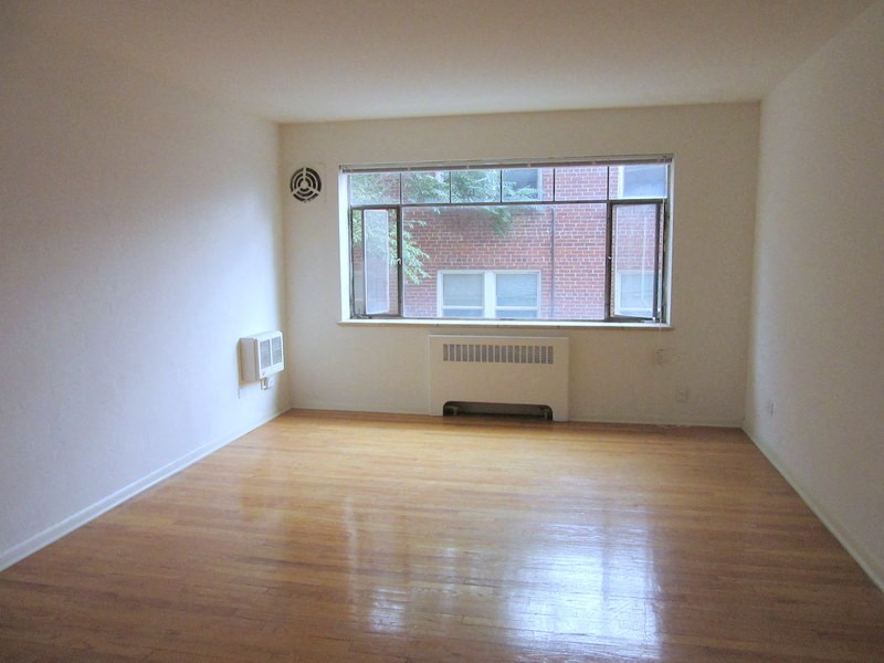 an empty room with a window and wooden floors