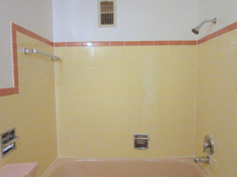 a yellow tiled bathroom with a shower and a sink