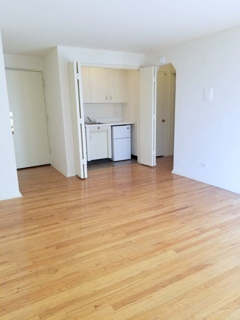 an empty living room and kitchen with wood flooring