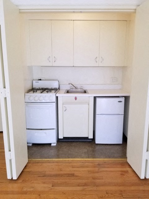 an empty kitchen with white appliances and white cabinets