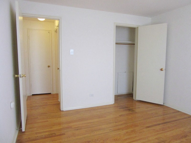 an empty room with a wood floor and white walls