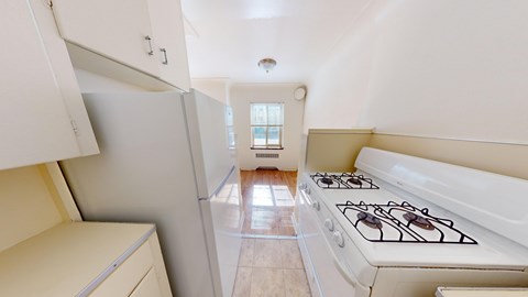 A white kitchen with a stove and a window.