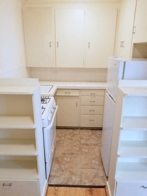 an empty kitchen with white cabinets and a stove and refrigerator