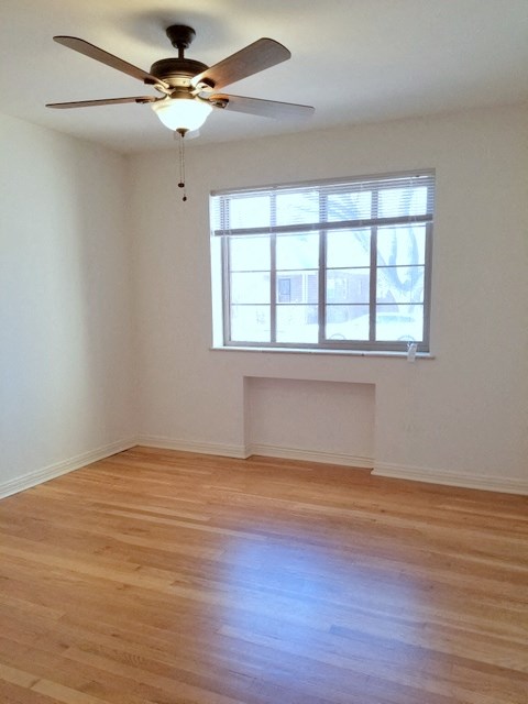 an empty room with a ceiling fan and a window
