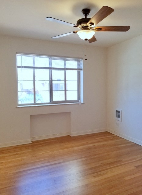 an empty living room with a ceiling fan and a window