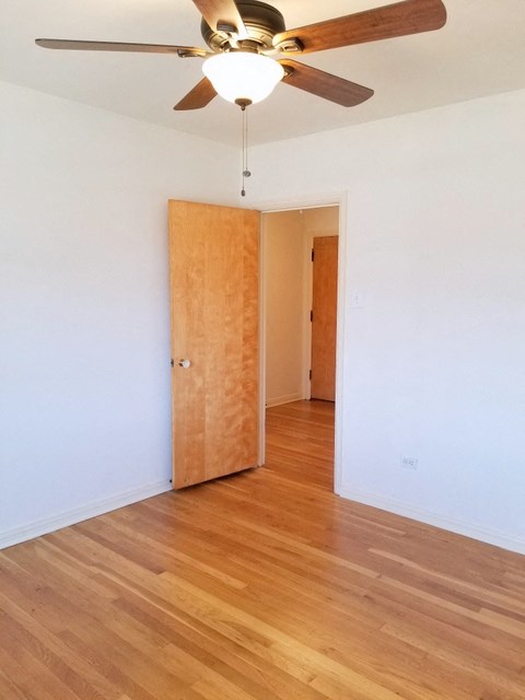 an empty room with a wooden floor and a ceiling fan