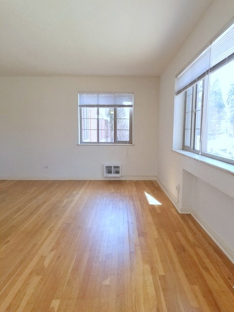 an empty living room with wood floors and two windows