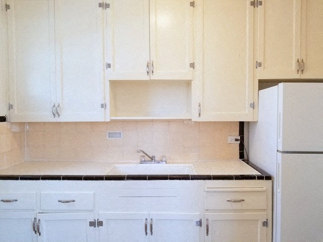 a kitchen with white cabinets and a sink and a refrigerator