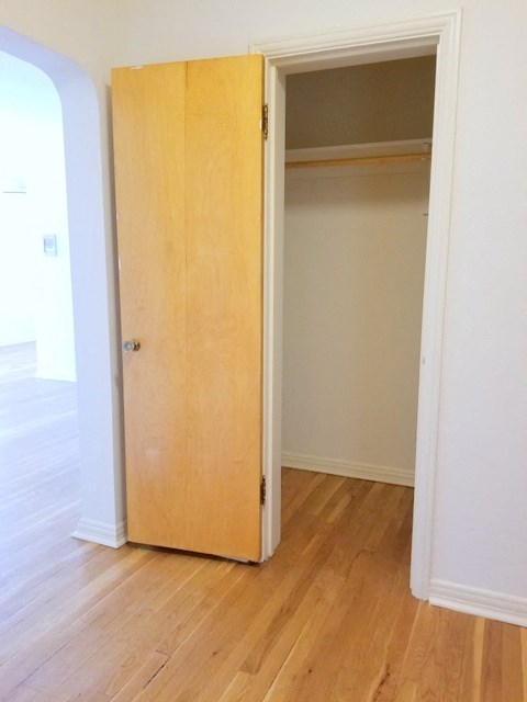 a closet in a room with a wooden floor and a door open