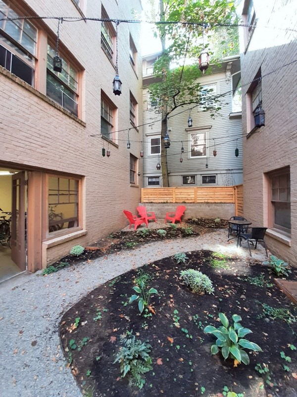 a courtyard with red chairs in front of a brick building
