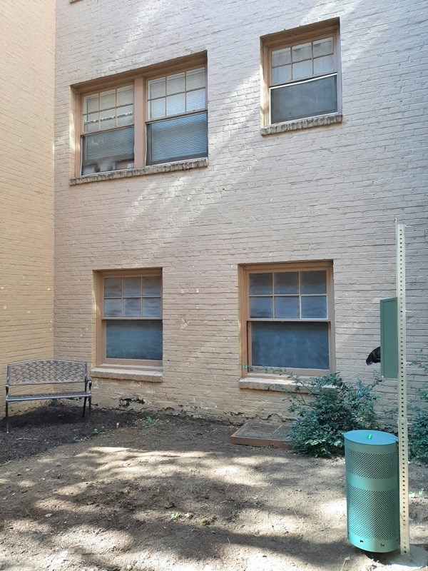 a white brick building with three windows and a bench