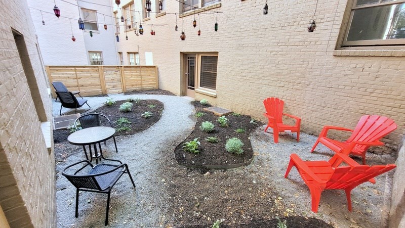 a patio with red chairs and a table outside of a brick building