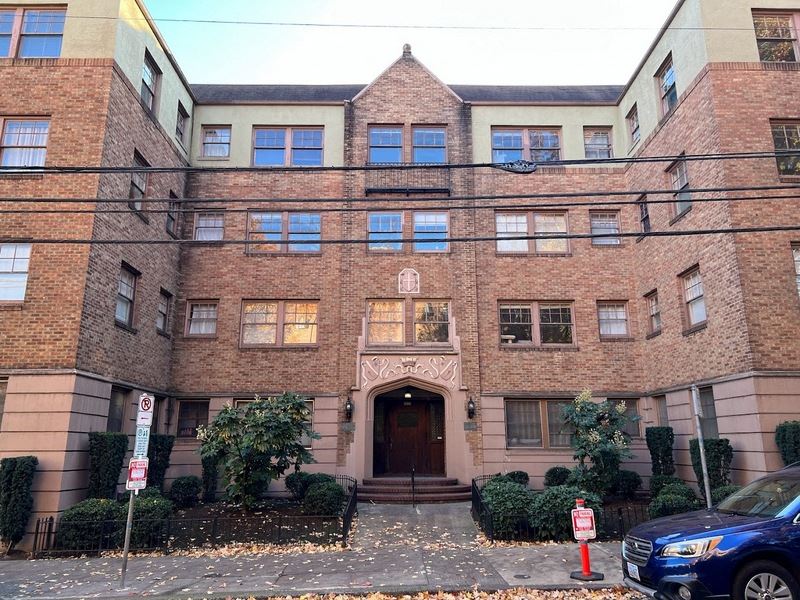 the front of a brick building with a car parked in front