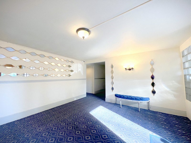 a room with a blue carpet and white walls and a blue bench